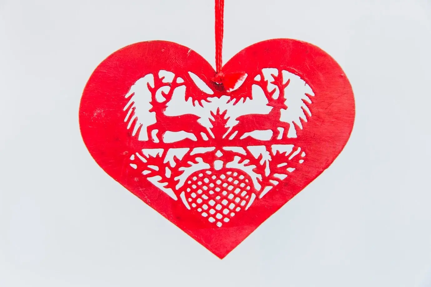Rotes, herzförmiges Weihnachtsornament auf weißem Hintergrund.